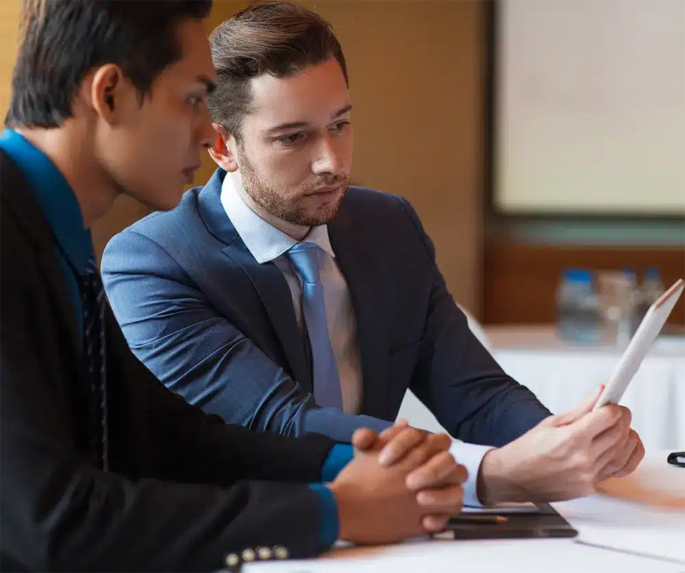 Two professionals in suits collaborating over legal documents, representing expert legal guidance for Lemon Law cases.