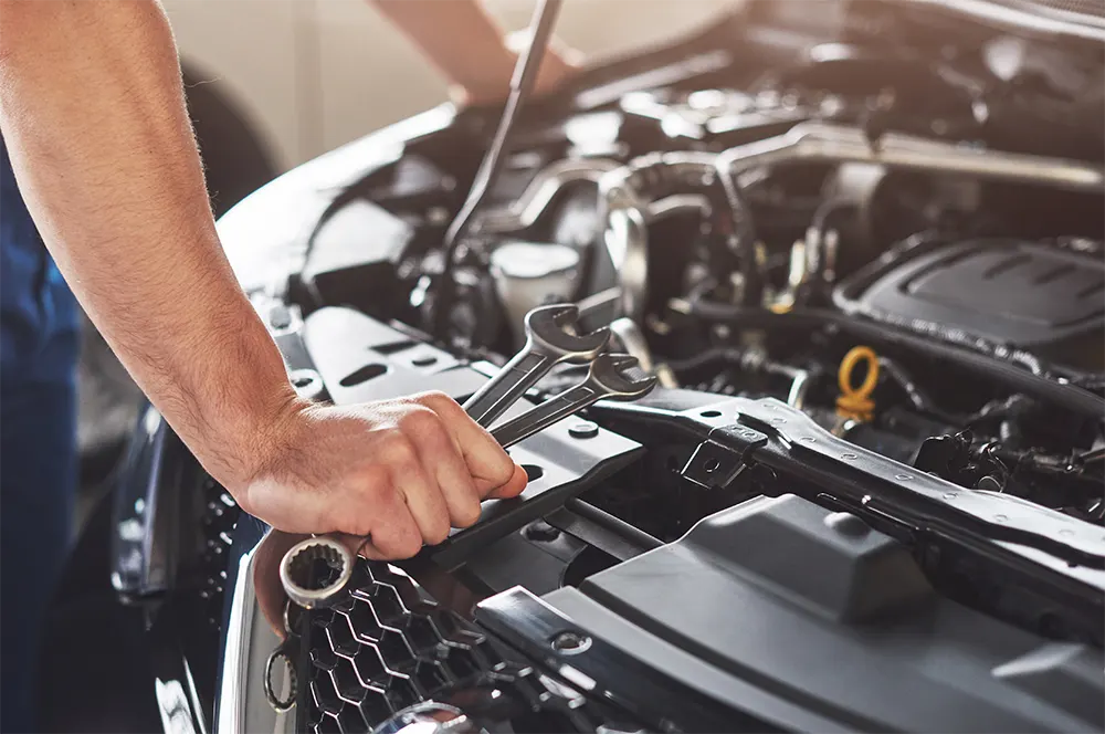 Close-up of a mechanic's hands using a wrench to work on a car engine.