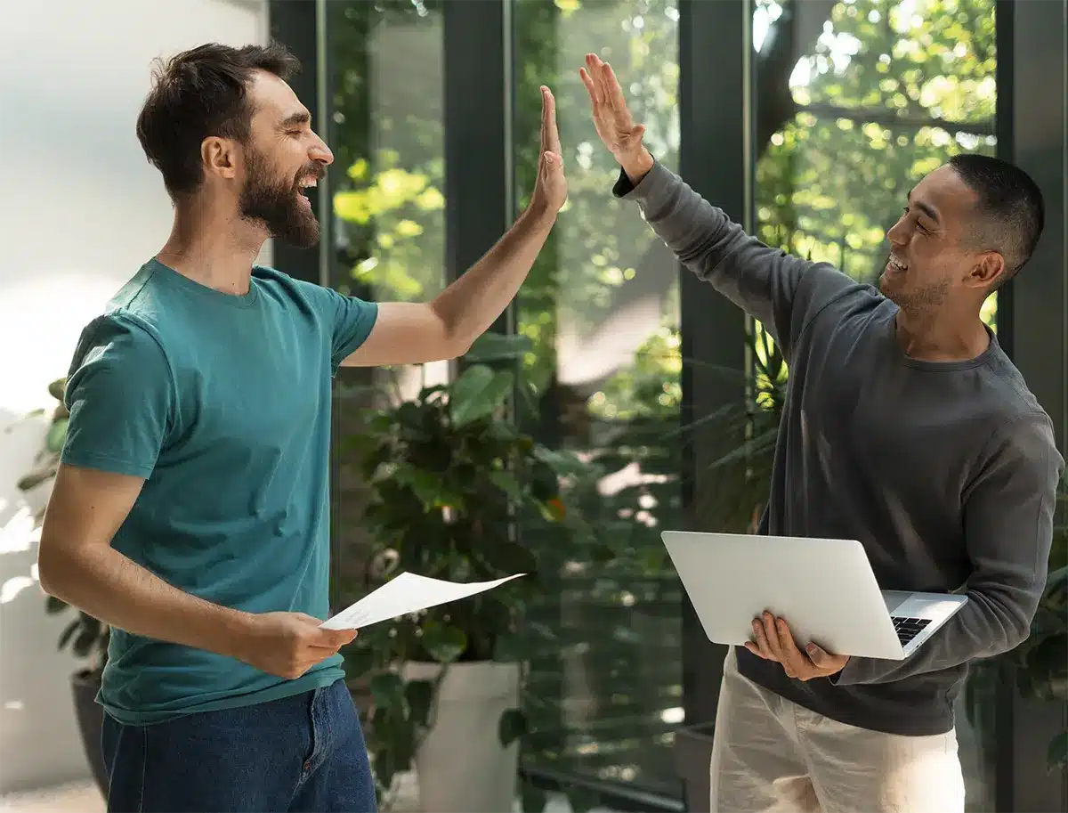Two smiling individuals celebrating success in a bright office environment, representing positive outcomes for Lemon Law clients.