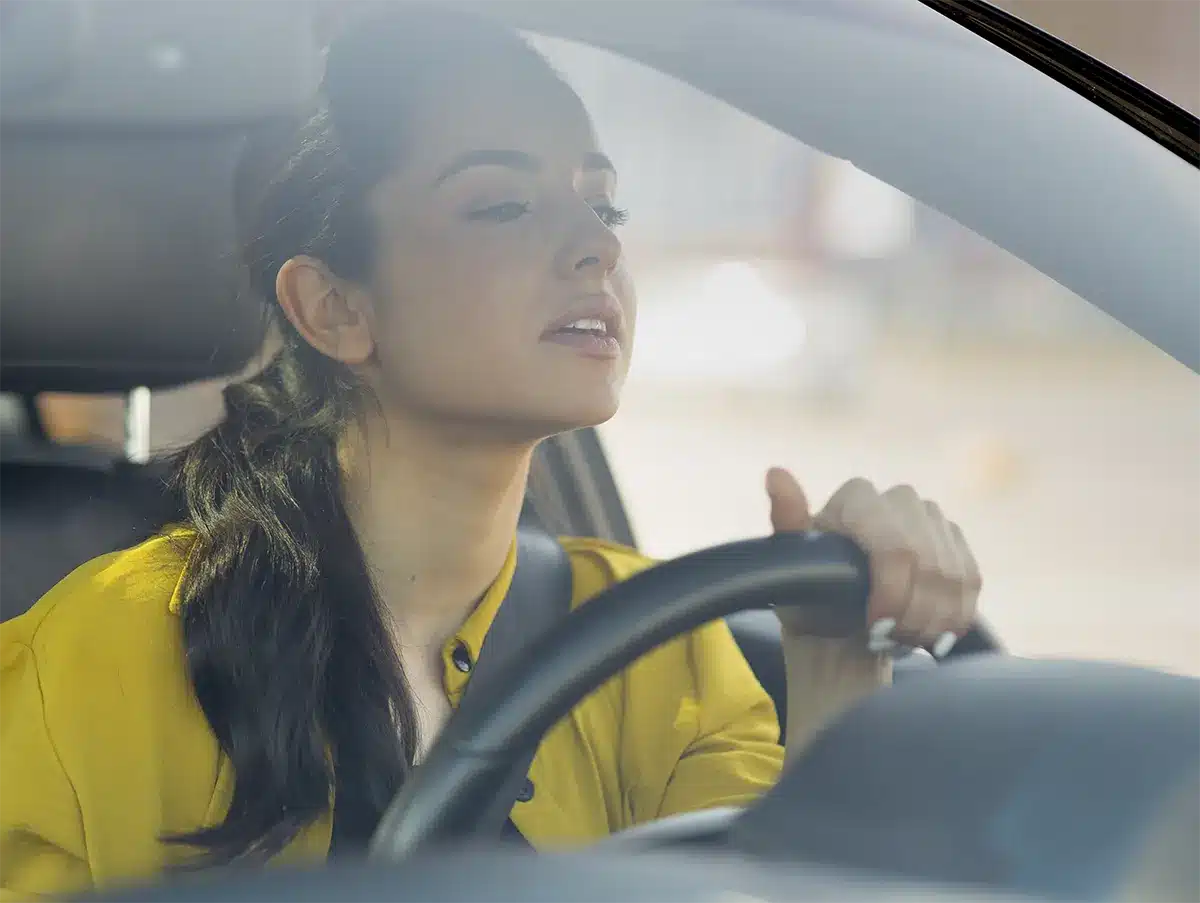 A woman enjoying the view near her car in a scenic mountain landscape, symbolizing freedom after resolving Lemon Law issues.