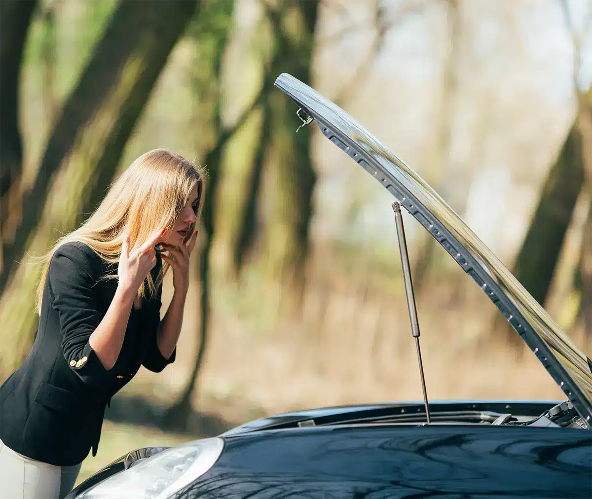 A concerned woman inspecting the hood of her car, symbolizing the frustration of dealing with a defective vehicle.
