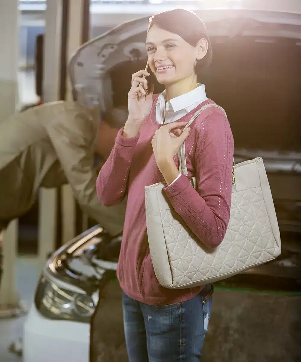 strip-img Smiling woman making a phone call in front of an open car hood, symbolizing relief while seeking Lemon Law assistance.