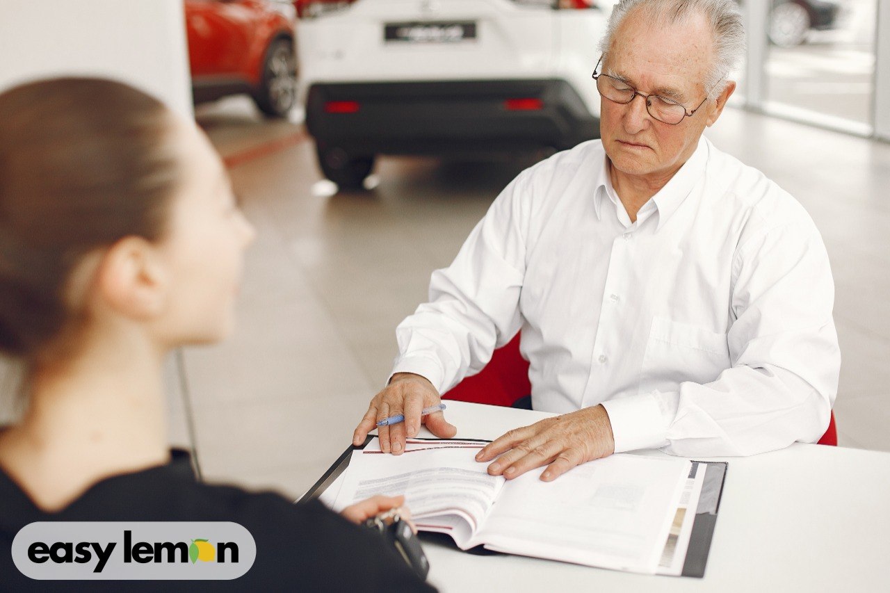 Car buyer reviewing paperwork with a dealership salesperson