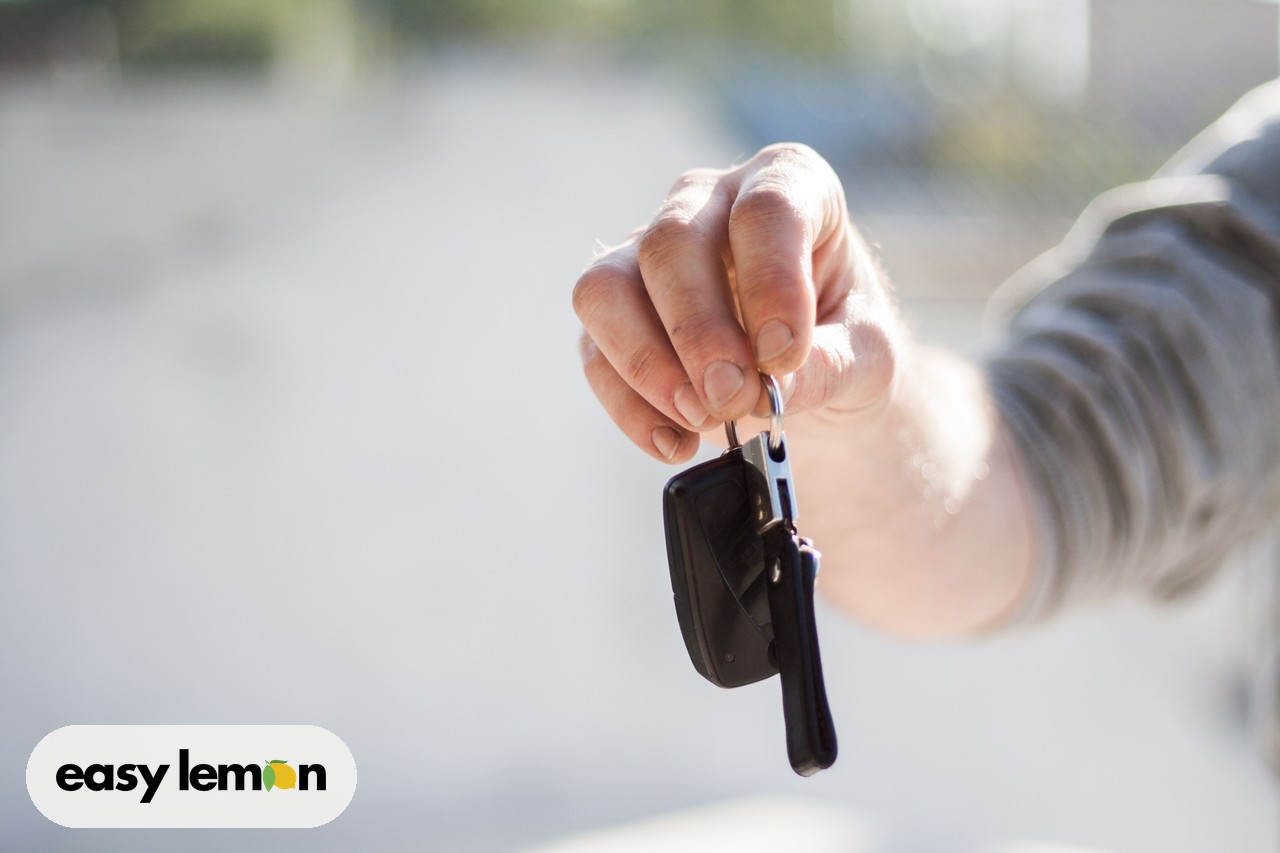 Close-up of car keys being handed over at a dealership, illustrating buying a car with possible open recalls