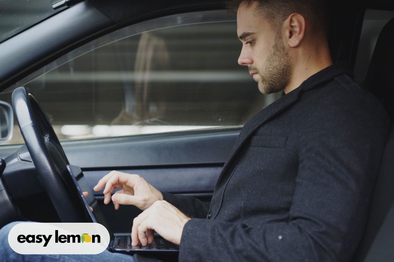 Focused car owner using a laptop inside a vehicle to check for open safety recalls