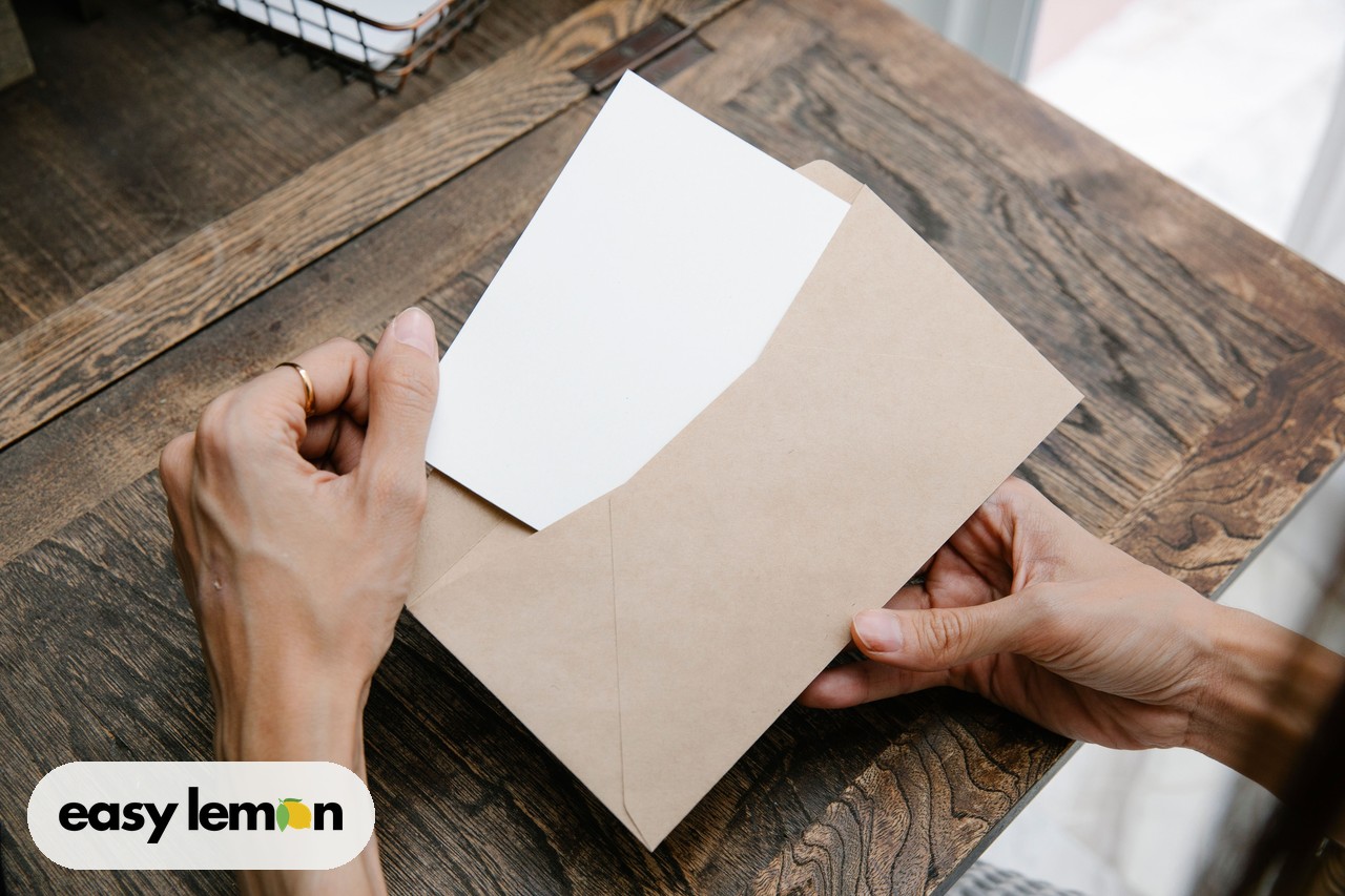 Hands opening an envelope containing a recall notice letter on a wooden desk